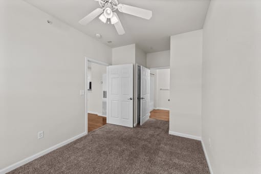 a spacious living room with carpet and a ceiling fan