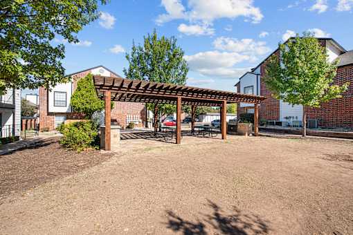 the backyard of a brick house with a wooden pergola