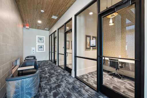 A hallway with a blue carpet and a wooden ceiling.
