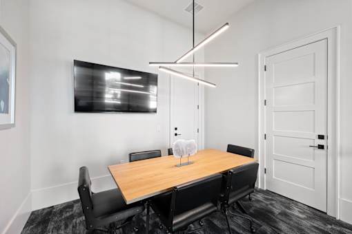 A modern dining room with a wooden table and black chairs.