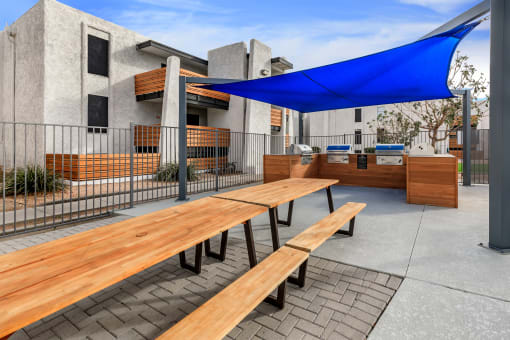 a picnic table with a blue awning in front of a building