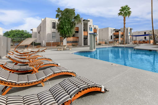 a pool with lounge chairs and palm trees in the background