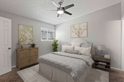 A bedroom with a bed, dresser, and ceiling fan.