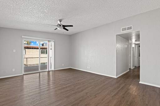 A room with a ceiling fan and sliding glass doors.