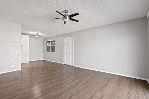 A room with a ceiling fan and wooden flooring.