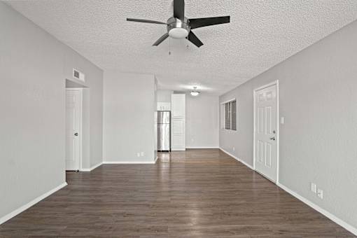 A spacious room with a ceiling fan and wooden flooring.