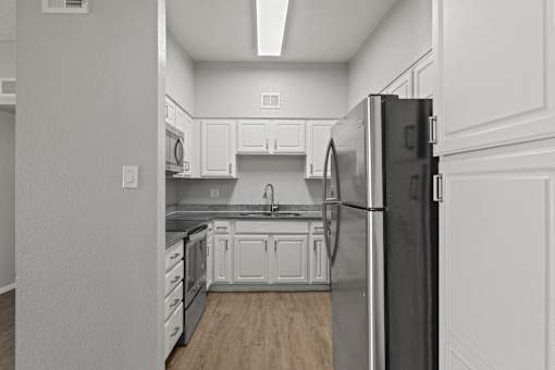 A kitchen with white cabinets and a black refrigerator.