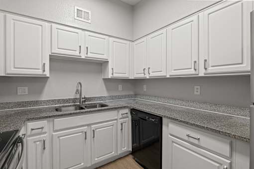A kitchen with white cabinets and a granite countertop.
