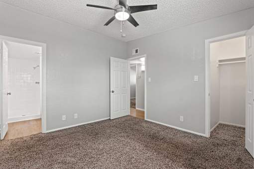 A room with a ceiling fan and carpeted floor.
