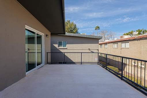 A patio with a black railing and a concrete floor.