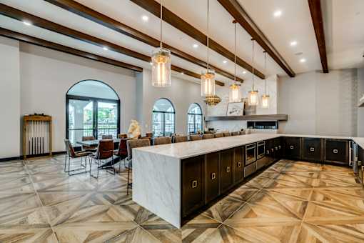 A large, well-lit kitchen with a marble countertop and a dining area with chairs and a table.