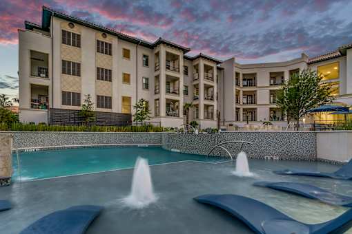 A large building with a pool in front of it.