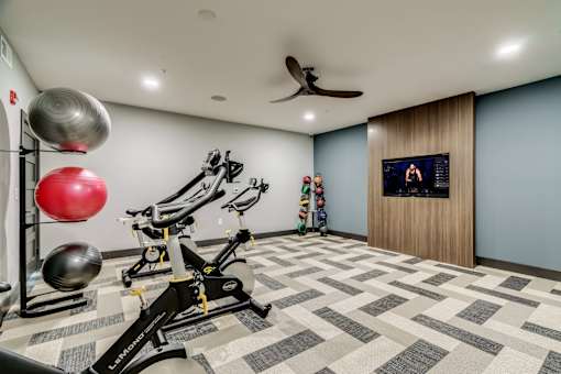 A home gym with a variety of exercise equipment and a television.
