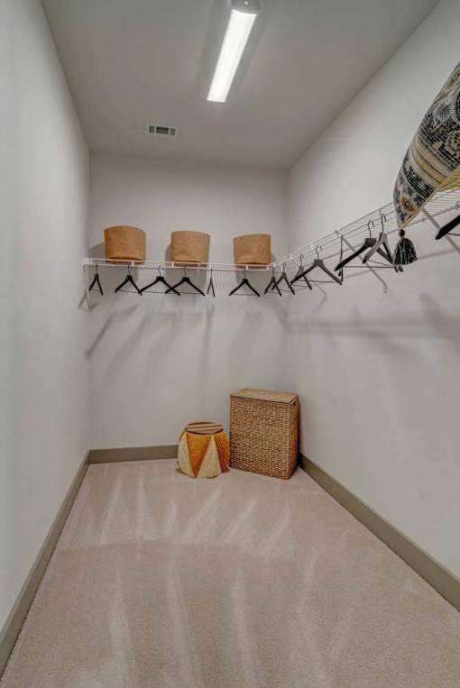 A room with a carpeted floor and a rack of hangers.