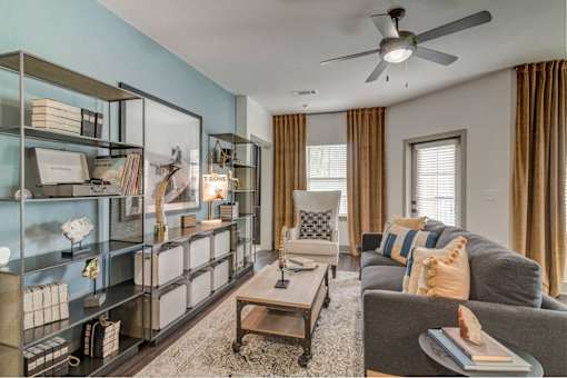 A living room with a grey couch, a coffee table, and a bookshelf.