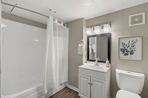 A white bathroom with a toilet, sink, and shower.