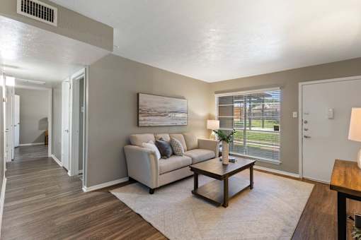 A living room with a couch, a coffee table, and a painting on the wall.