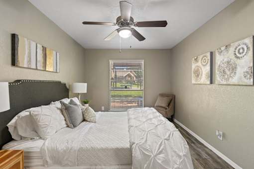 A bedroom with a large bed and a ceiling fan.