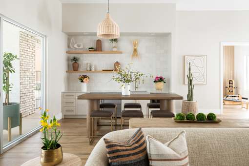 A living room with a couch, a table, and a potted plant.