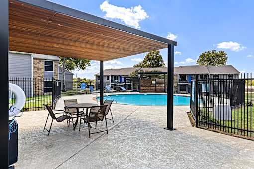 A patio with a table and chairs and a pool.