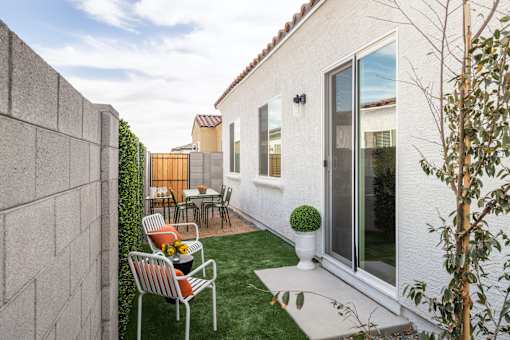 A patio with a table and chairs is surrounded by a wall and a tree.