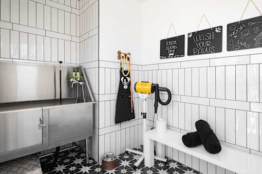 A bathroom with a white tiled wall and a black and white floor.