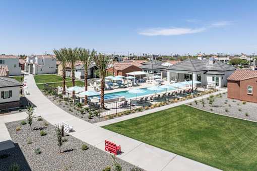 A pool surrounded by palm trees and a red bench.