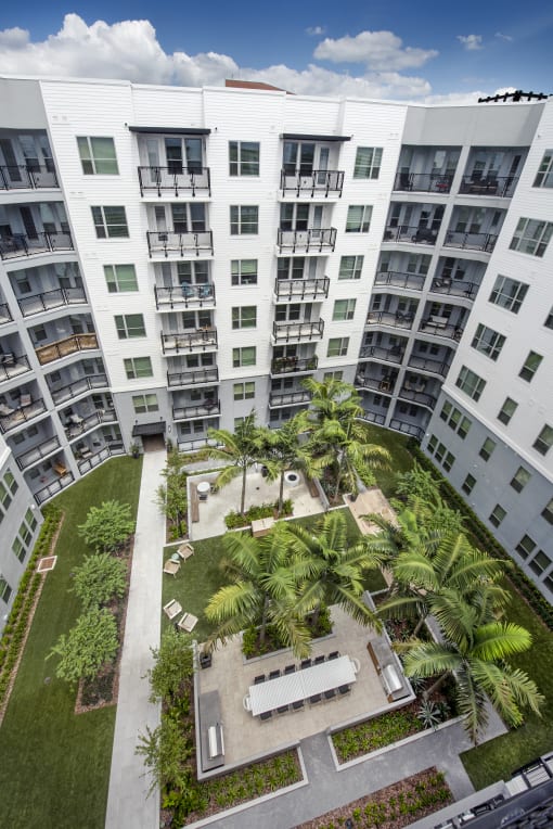 an aerial view of an apartment building with a courtyard and palm trees