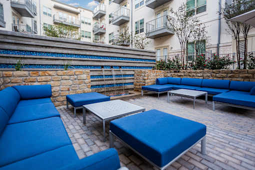 A blue couch and table set up on a brick patio.