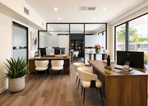 A modern office with a glass partition and a view of the outside.