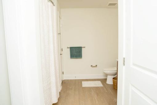 A bathroom with a toilet, a mat, and a towel hanging on the wall.