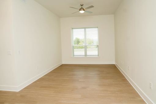 Empty room with a window and a ceiling fan.