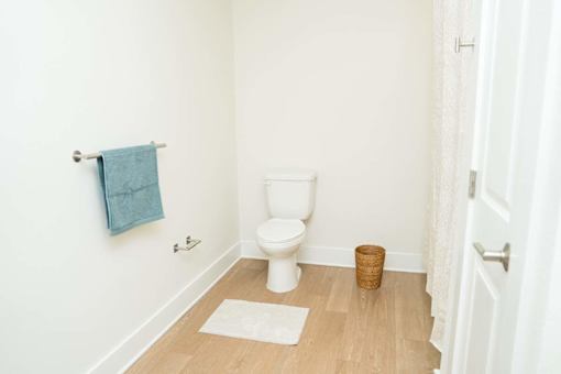 A white toilet in a small bathroom with a blue towel hanging on the wall.