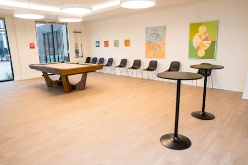 A room with a long table and chairs and paintings on the wall.