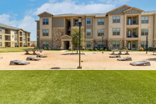 a picnic area with benches and a lamppost in front of an apartment building