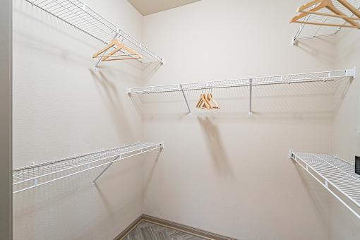A walk-in closet with three shelves and hangers.