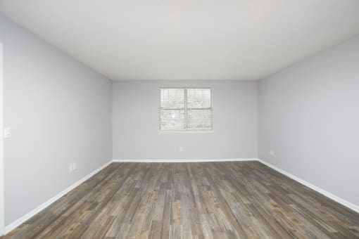 an empty room with hardwood floors and a window