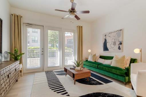 A living room with a green couch and a ceiling fan.
