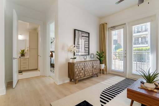A modern living room with a wooden bench and a black and white rug.