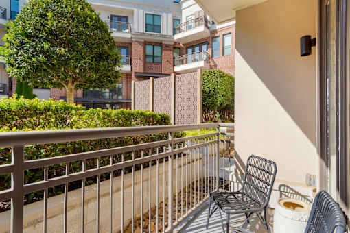 A balcony with a chair and a tree in front of a building.