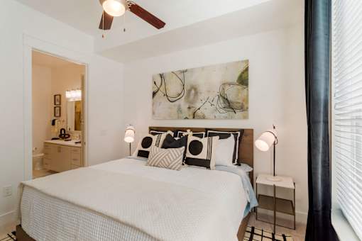 A bedroom with a large bed and a ceiling fan.