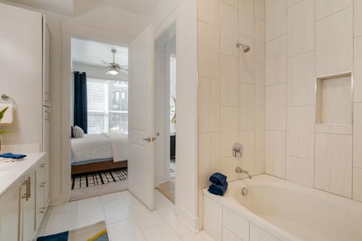 A white bathroom with a tub, sink, and mirror.