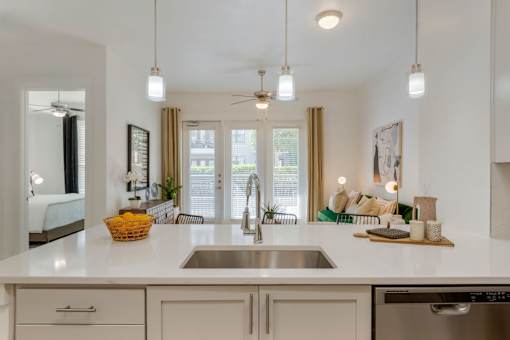 A kitchen with a white countertop and a stainless steel sink.