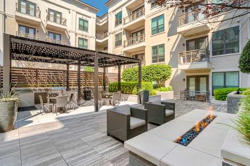 A patio with a fire pit and seating area in front of apartment buildings.