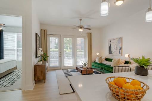 A living room with a white couch and a basket of oranges on the table.