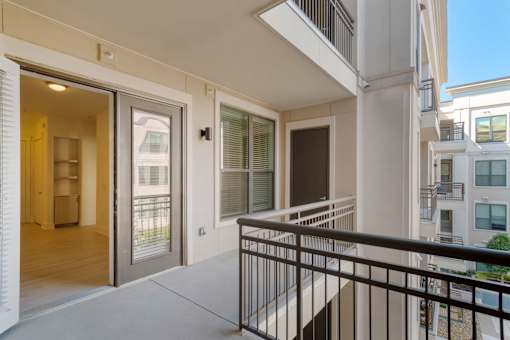 A balcony with a black railing and a view of other buildings.