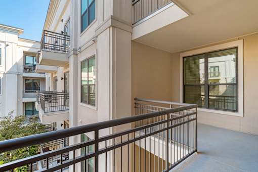 A balcony with a black railing and a window with green blinds.