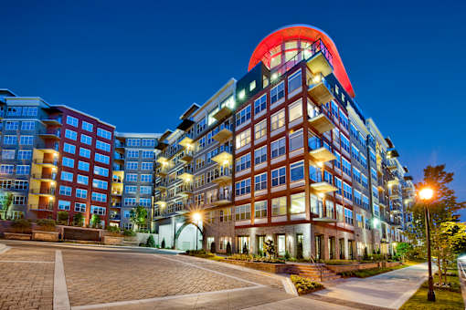 A modern multi-story building with a red and blue top is illuminated at night.