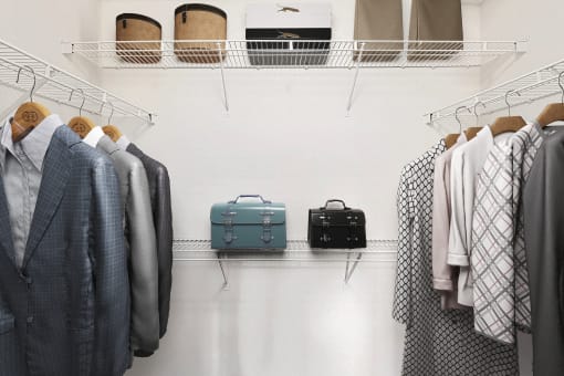 a closet filled with suitcases and clothes on a rack