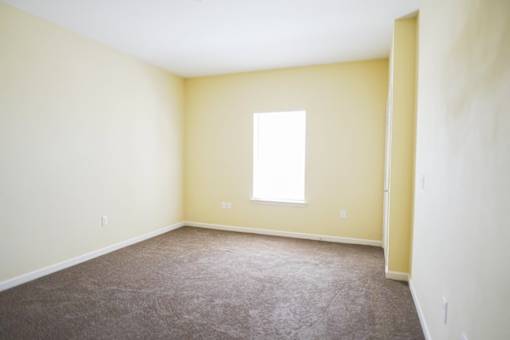A room with a carpeted floor and a window.